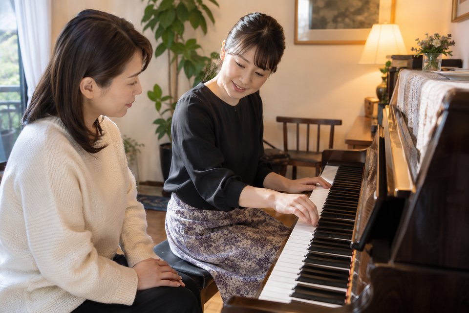 手元を見ながら丁寧に教える音楽講師（AI生成イメージ）