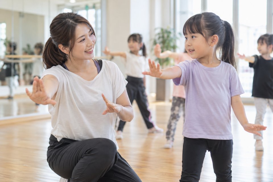 子どもの目線で動きを説明するダンス講師（AI生成イメージ）