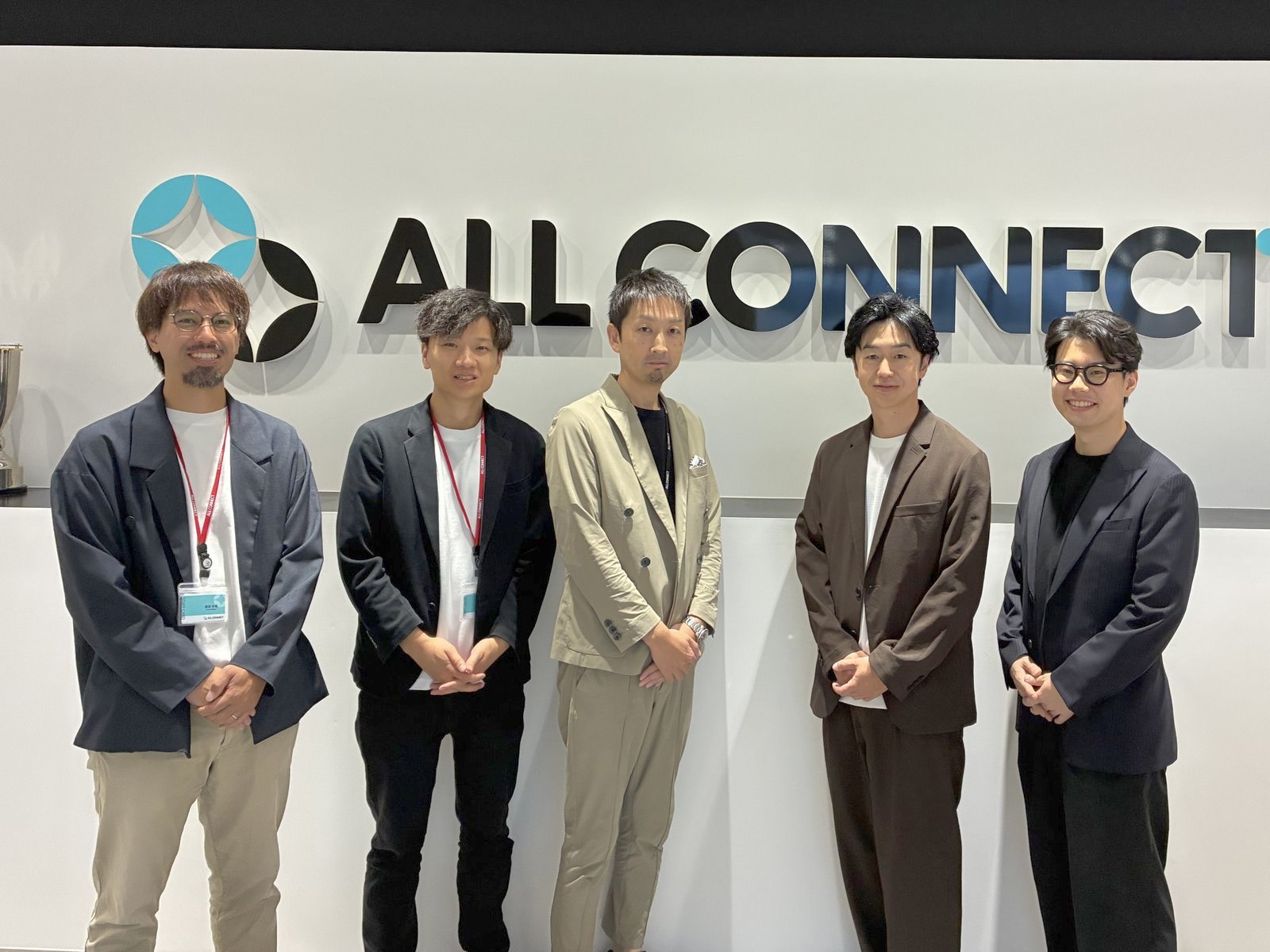 株式会社ALL CONNECTの本社エントランスに並ぶ、株式会社ALL CONNECTとデジタルアスリート株式会社のメンバー